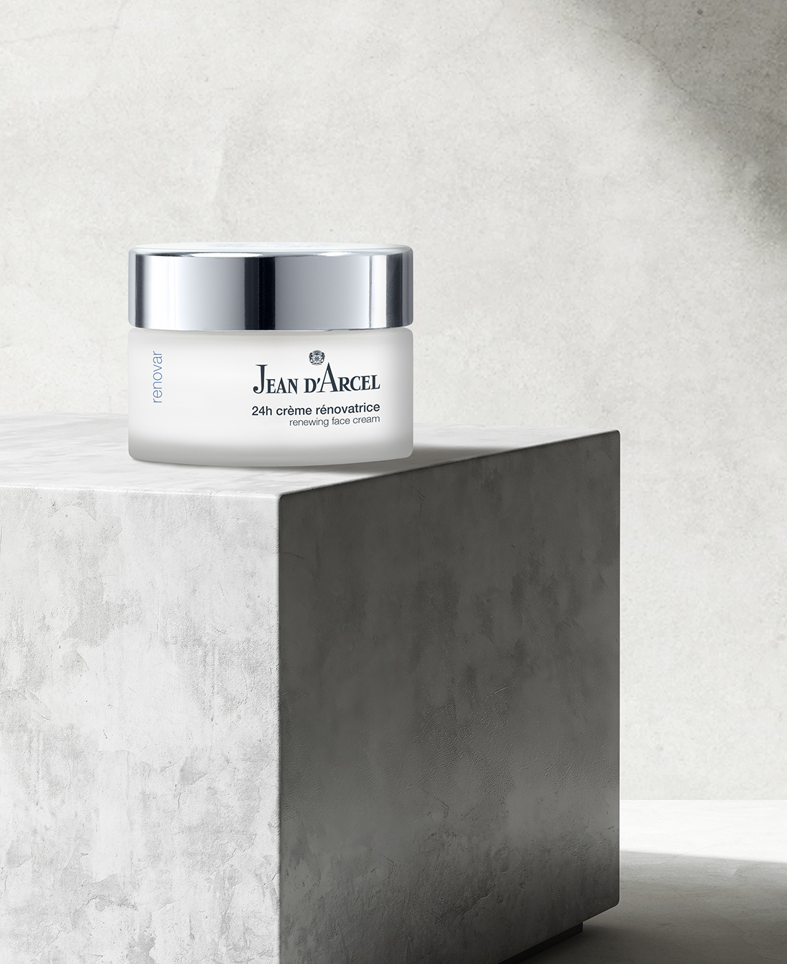 Glastiegel mit silbernem Deckel, präsentiert auf einem gestuften, hellgrauen Podest.